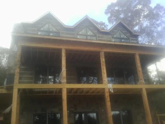 Dormers and porch framing on a large log home under construction — Roof Coating work by our crew in Trezevant