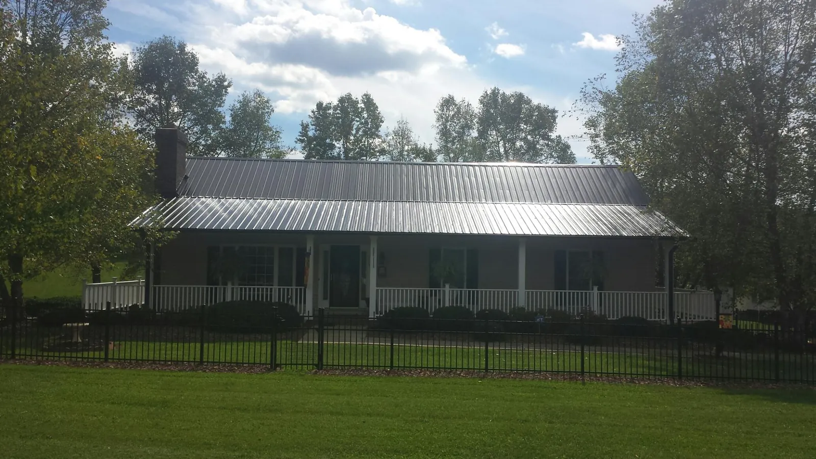 Gray metal roof on a brick ranch with a full width front porch — Gutter Guard Installation work by our crew in Trezevant