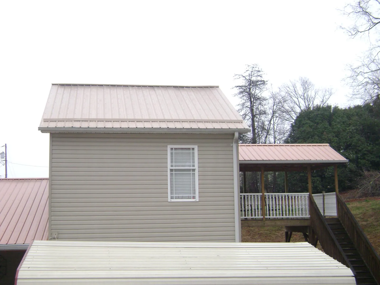 Tan metal roofs on a two story addition and attached porch, from a Roof Replacement job in Trezevant